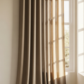 Natural flax weighted linen drape by a window